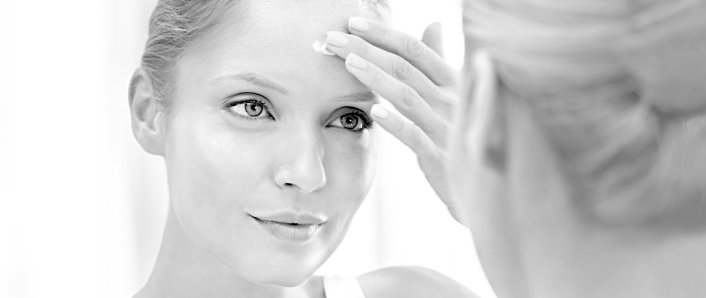 Femme s'appliquant de la crème sur le front